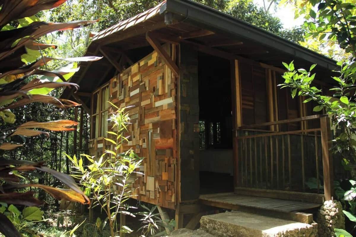 A rustic wooden cabin with a wooden facade and a wooden deck.