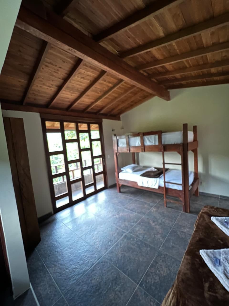 Une pièce avec un lit superposé, un sol carrelé et un plafond en bois.