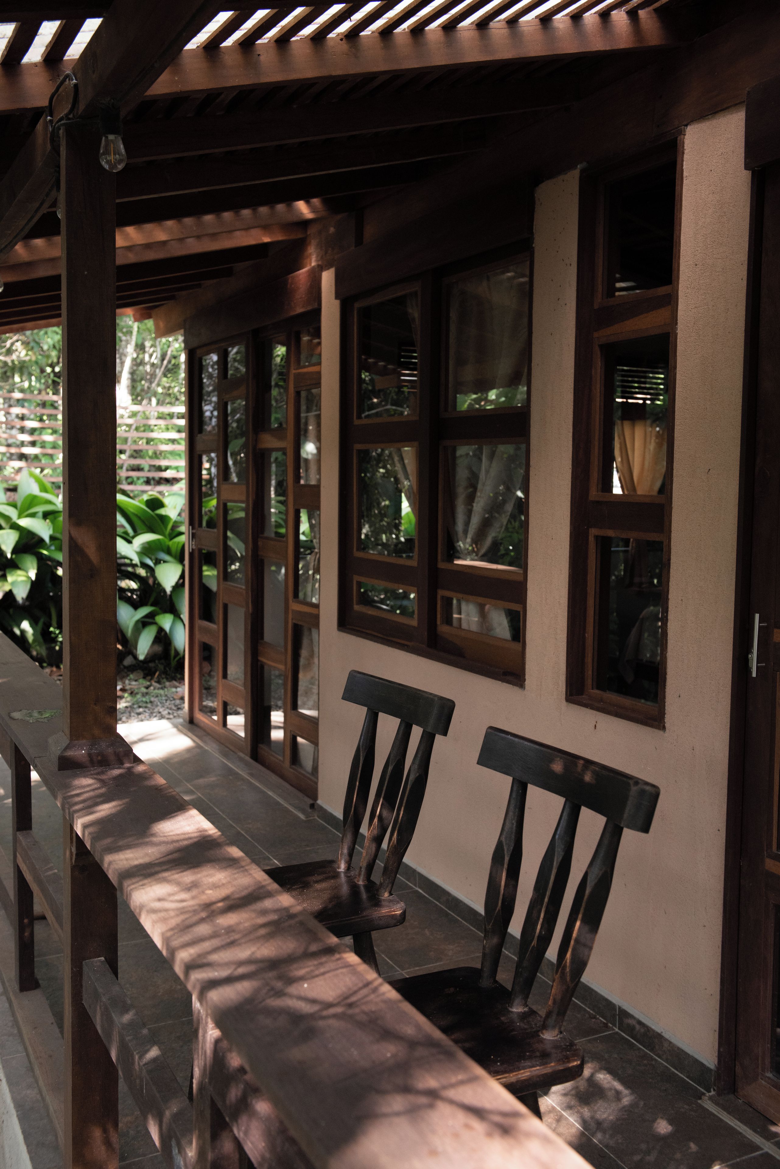 A wooden bench under a covered area with a view of greenery outside.