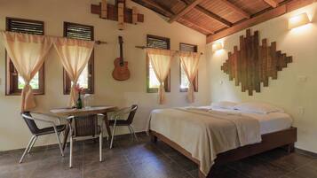 A bedroom with a bed, a guitar, and a dining area with chairs and a table.