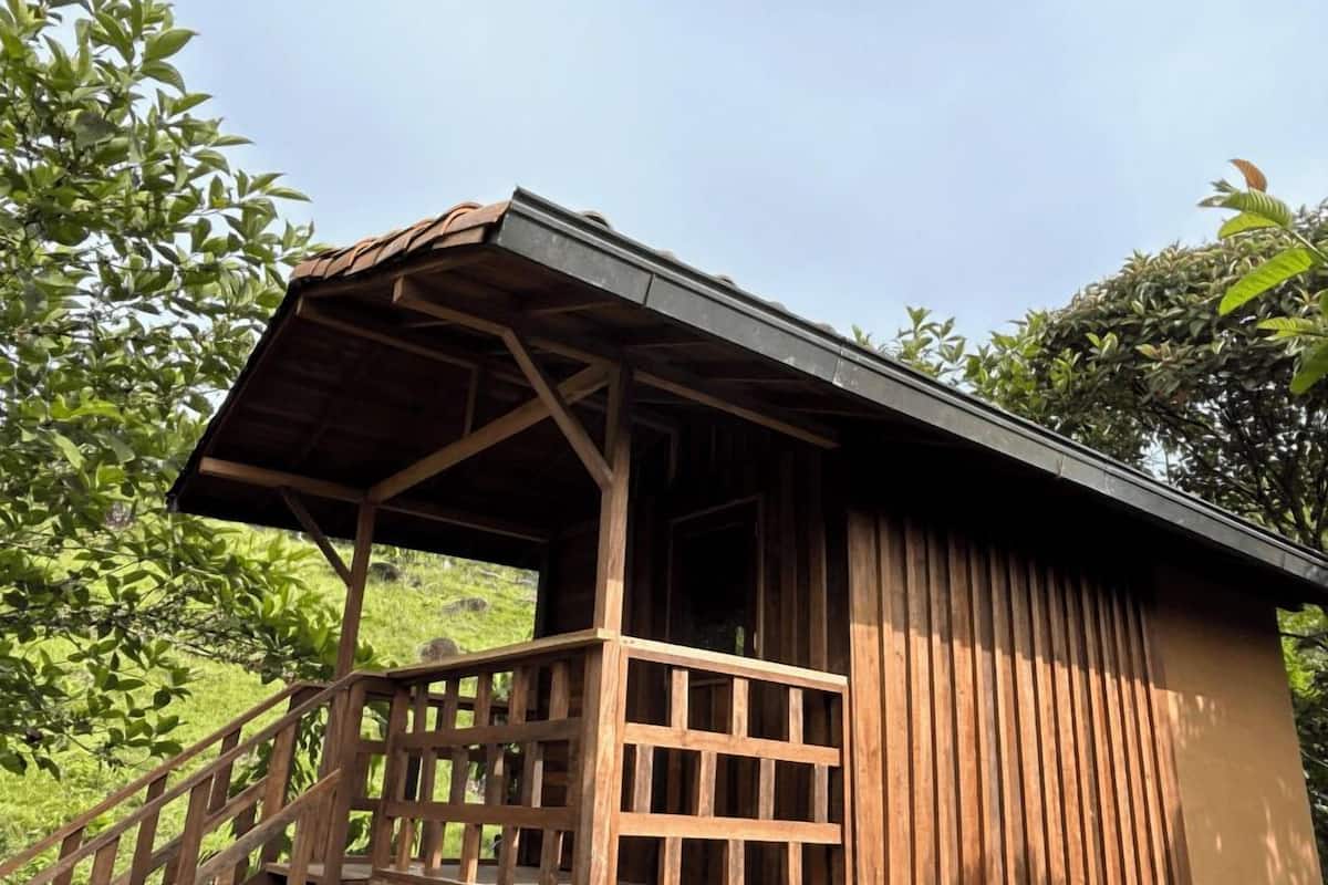 A wooden cabin with a sloped roof and a wooden staircase leading to a balcony.