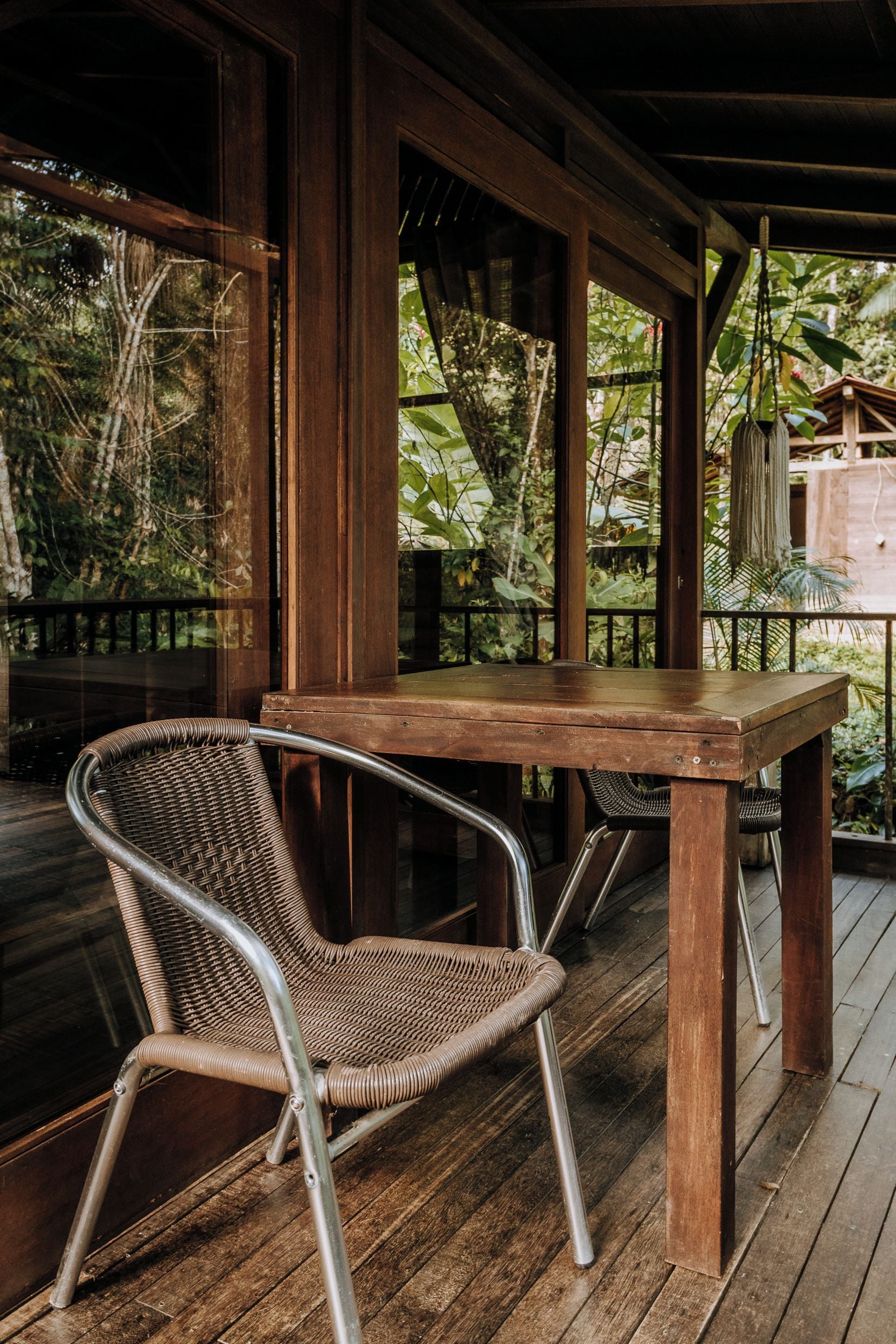 A wooden deck with a table and a wicker chair.