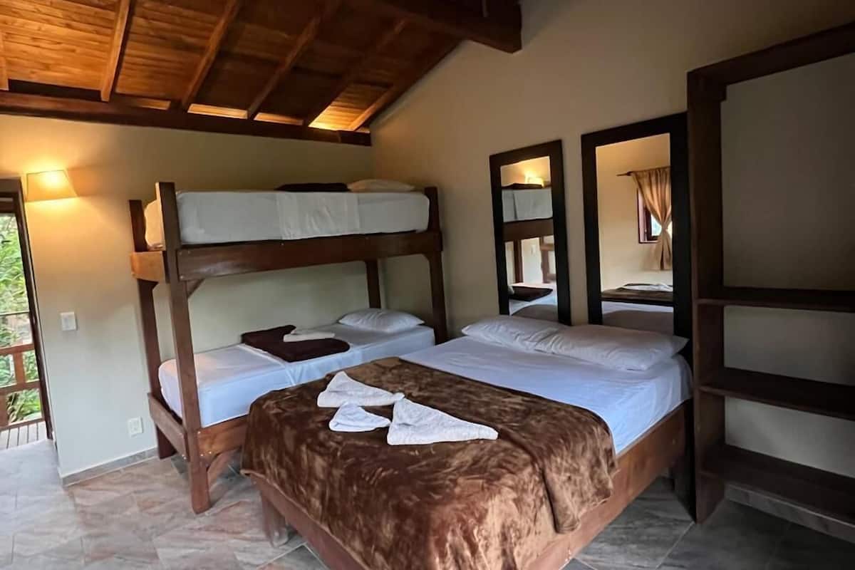 A room with two wooden bunk beds, a brown blanket, and a mirror on the wall.