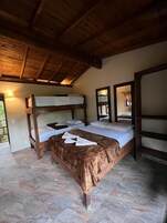 Una habitación con dos literas de madera, una manta marrón y un espejo en la pared.