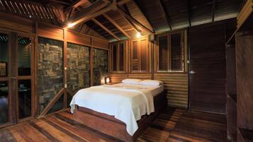 Una habitación de madera con una cama, pared de piedra y vigas de madera en el techo.