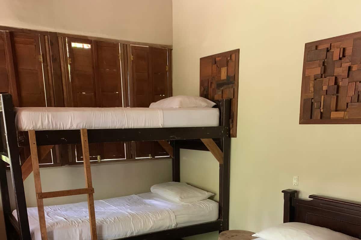 A bunk bed room with a blue blanket and pillows, a wooden headboard, and a wall-mounted artwork.
