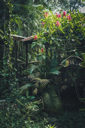A lush garden with a wooden pergola, dense foliage, and flowering plants. - Ritmo Del Rio - Hotel y Restaurante (San Rafael)