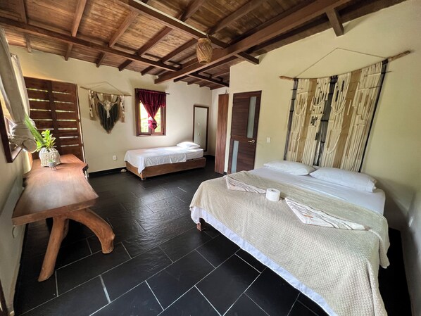 A room with a wooden ceiling, two beds, a small table with a plant, and a window with curtains. - Ritmo Del Rio - Hotel y Restaurante (San Rafael)