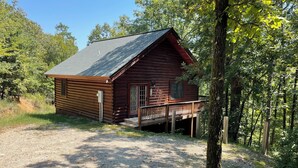 A wooden cabin with a porch, surrounded by trees and a gravel path. - Cozy mountain cabin 15 minutes from historic downtown, 3 miles from ORV PARK  (Hot Springs National Park)