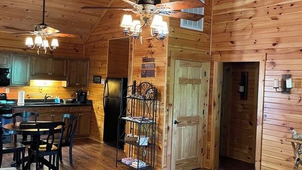 A wooden cabin interior with a dining area, kitchen, and a cozy seating space. - Cozy mountain cabin 15 minutes from historic downtown, 3 miles from ORV PARK  (Hot Springs National Park)
