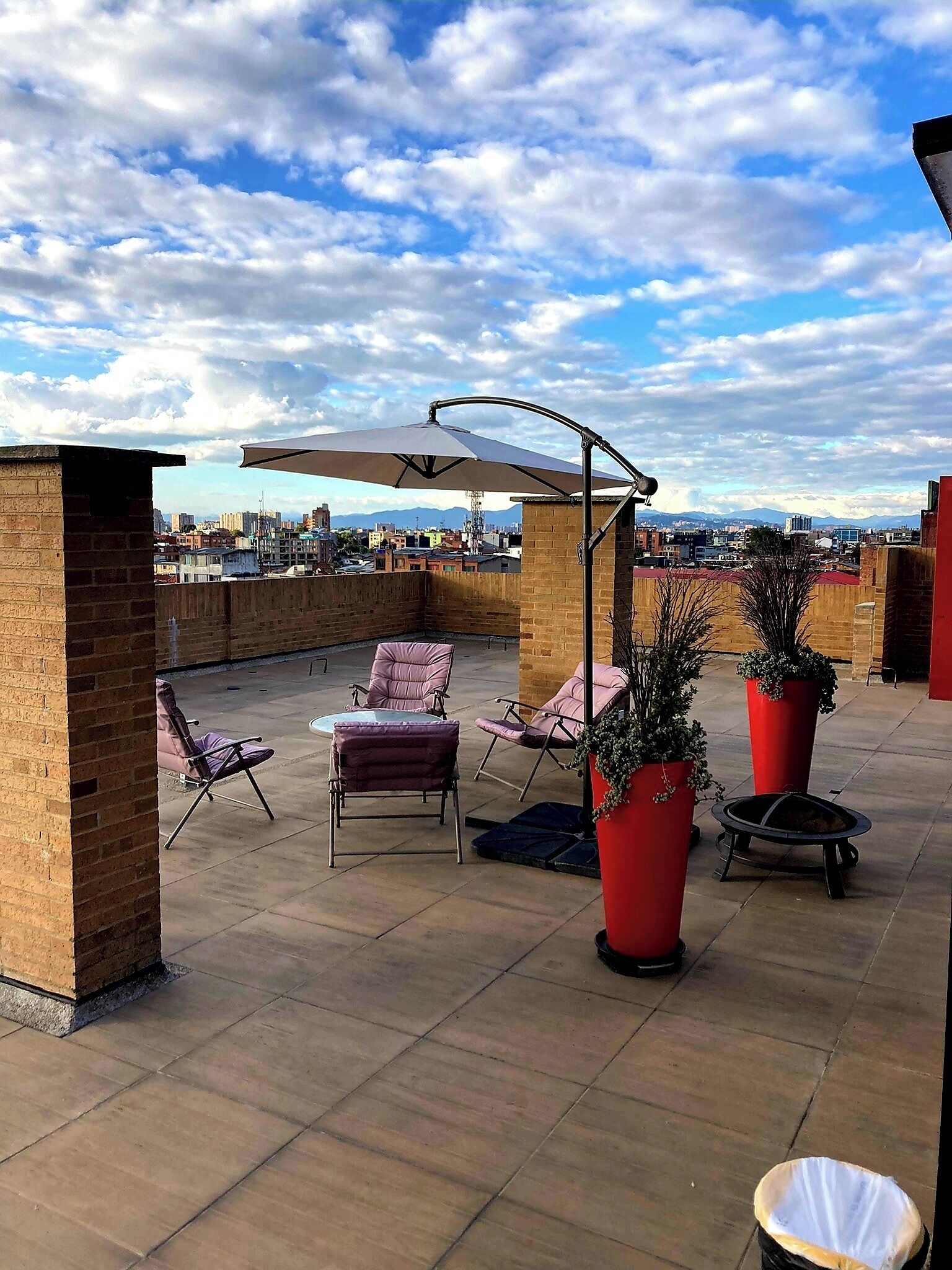 Una terraza en la azotea con mobiliario exterior, un brasero y plantas en macetas.