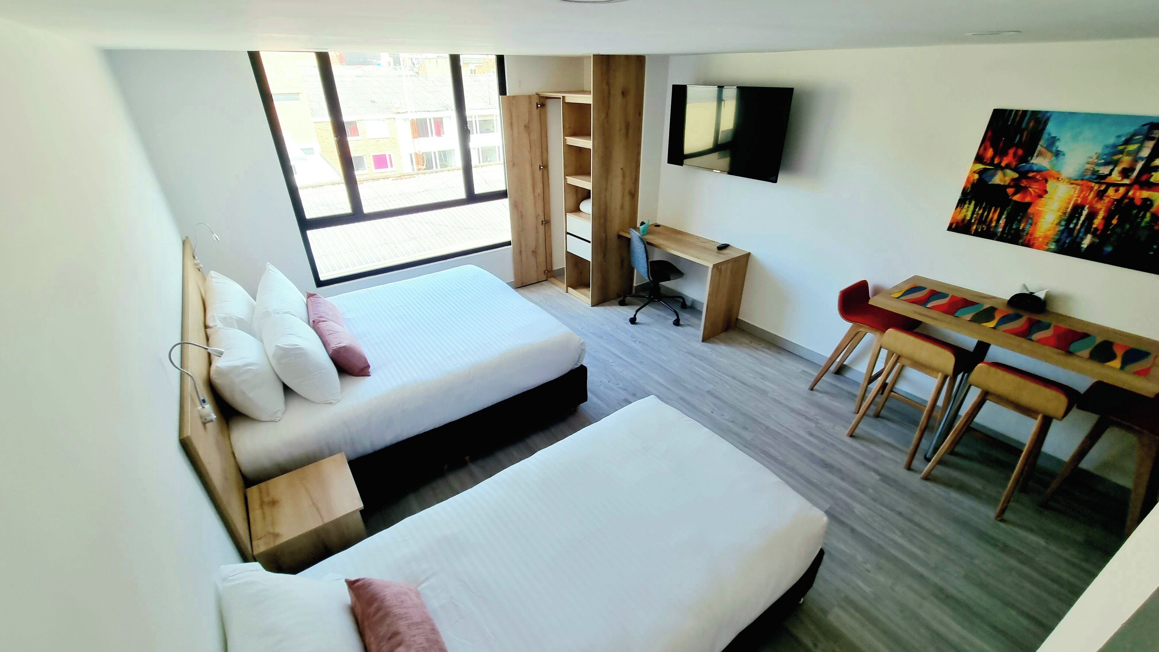 A hotel room with two beds, a desk, a chair, a TV, and a painting.