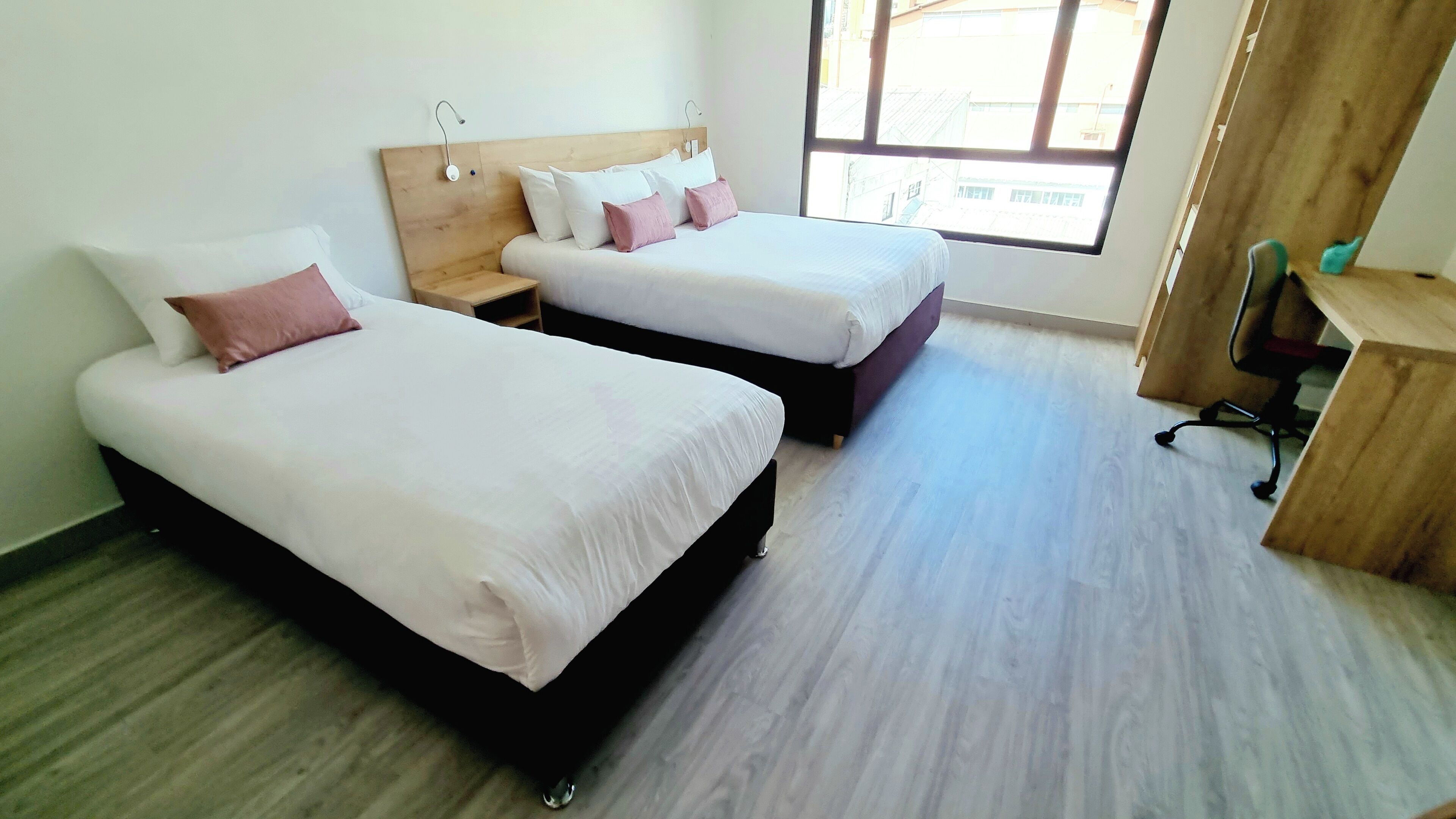 A hotel room with two beds, a desk, and a chair.