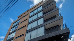 A modern building with a sign reading "Toscana LOFT APARTMENTS" and an address "Calle 52 #14-83".