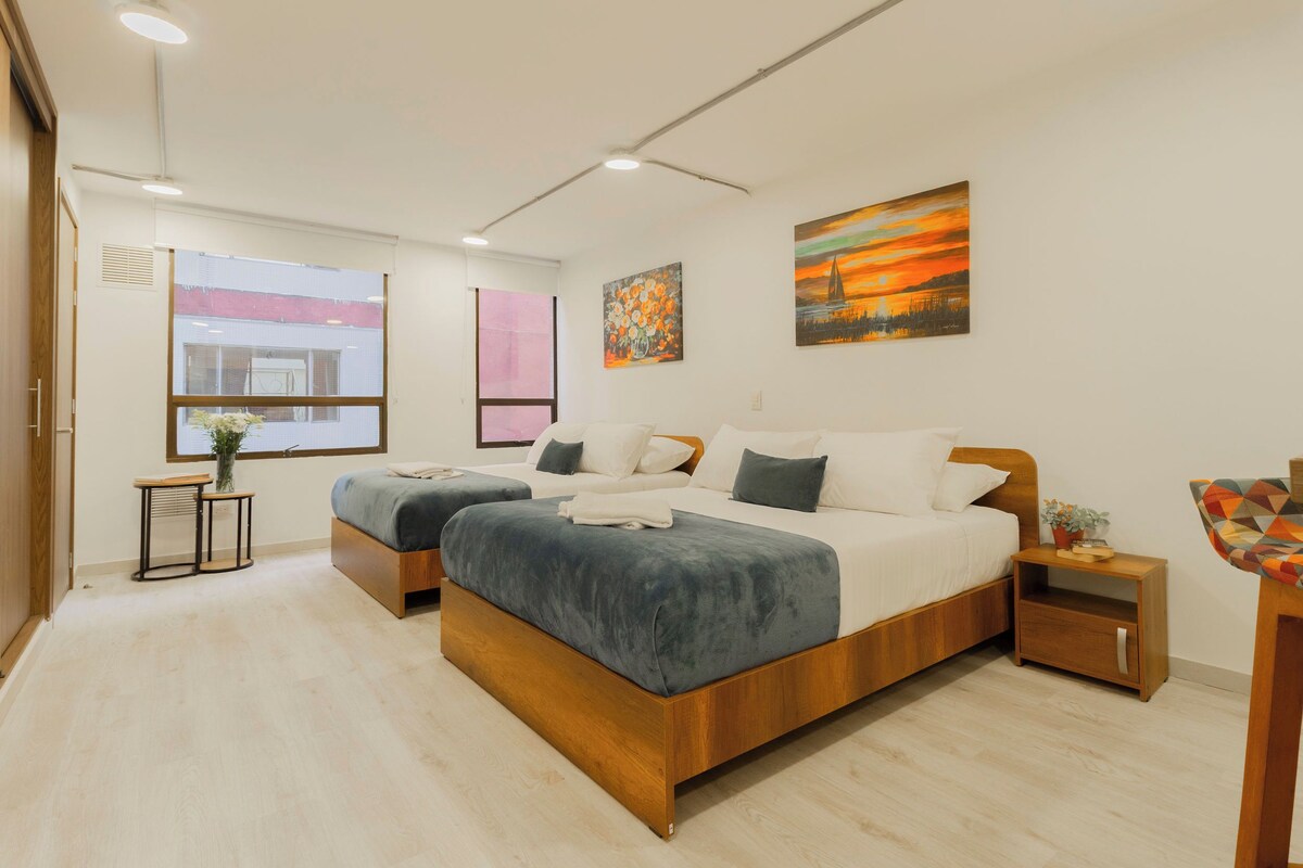 A modern bedroom with two beds, a bedside table, a nightstand, and artwork on the walls.