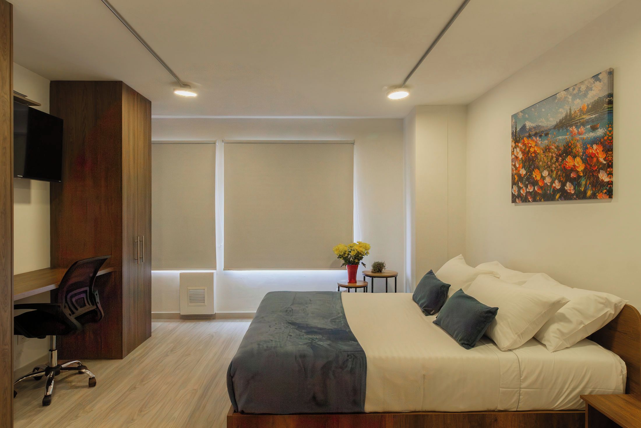 Ein modernes Schlafzimmer mit einem Bett, einem Schreibtisch und einem Stuhl. Ein Fenster bietet Blick ins Freie.
