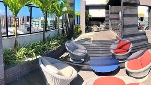 A rooftop terrace with wicker furniture, a pool, and a view of the cityscape. - Vacanze - Time (Maceió)