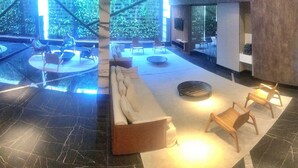 A modern lobby with a marble floor, seating areas, and a view of greenery outside. - Vacanze - Time (Maceió)