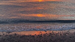 Un coucher de soleil sur une mer calme, avec un horizon dégagé.
