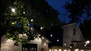 Um pátio com móveis de jardim e luzes de cordão.