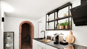 Eine kleine Küche mit einer Ziegelbogenarchitektur, einer eingebauten Ablage für Gläser, einem Toaster und einer Kaffeemaschine.