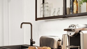 Eine moderne Küche mit schwarzer Arbeitsplatte, einem Toaster, einer Kaffeemaschine und einem Brot.