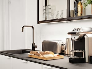 A modern kitchen with a black countertop, a toaster, a coffee machine, and a loaf of bread. - Charm 3 - Cozy 1-bdr Apt With Shared Garden (Copenhagen)