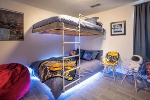 Ein Stockbett mit einer Leiter, ein roter Sitzsack, ein Schreibtisch mit Stuhl und ein Poster an der Wand.