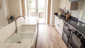 Una cocina moderna con encimera de mármol, electrodomésticos de acero inoxidable y vistas al exterior.
