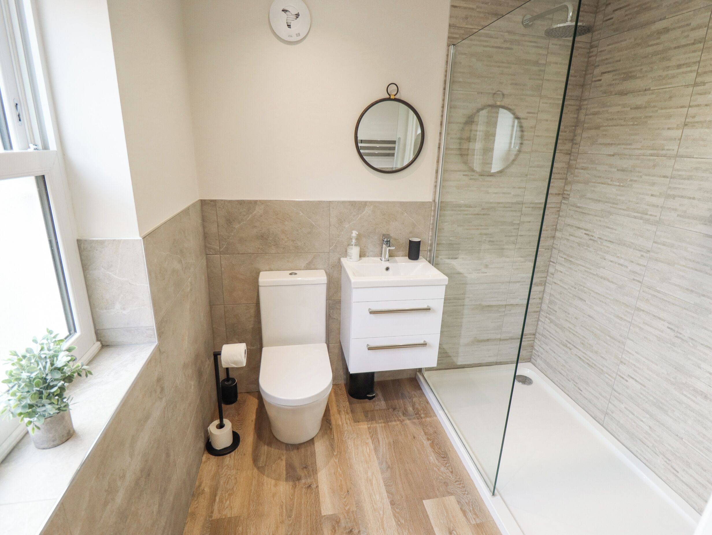 Un baño moderno con inodoro, lavamanos y cabina de ducha de vidrio.