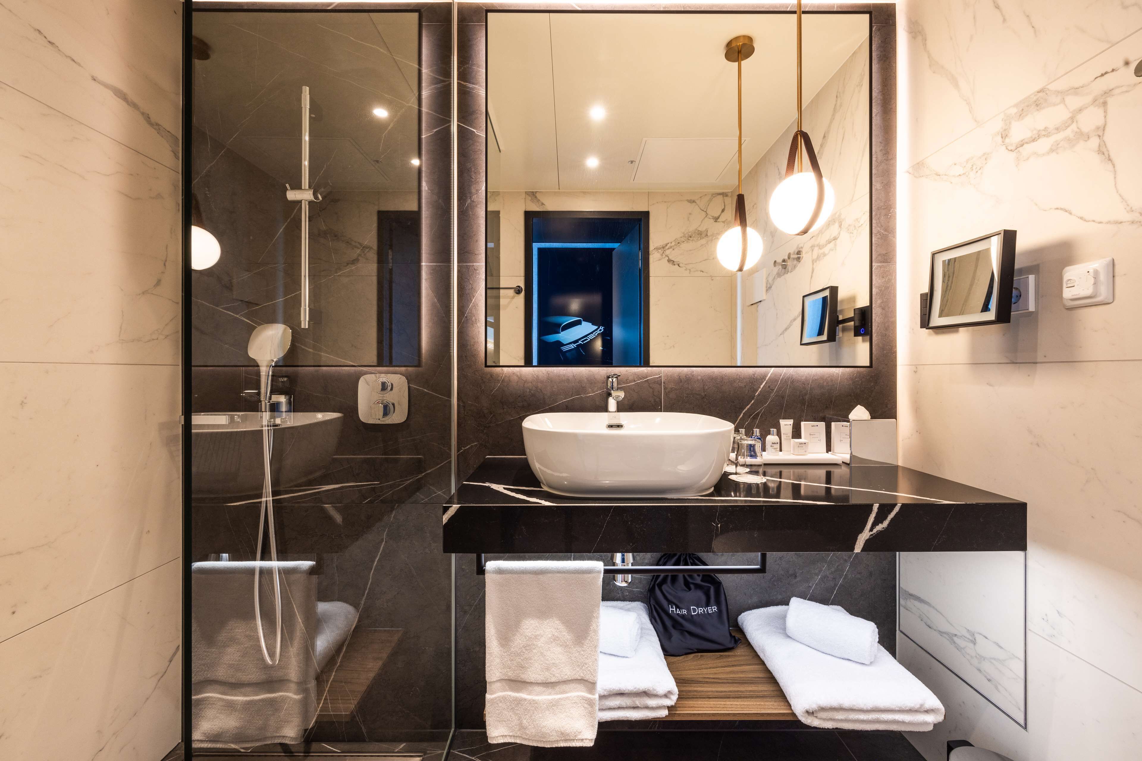 Une salle de bain moderne avec un grand miroir, un lavabo, une douche et un porte-serviettes.