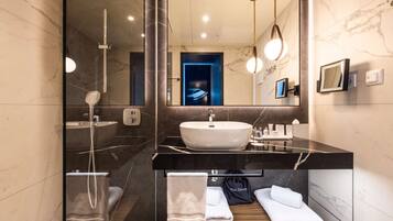 Une salle de bain moderne avec un grand miroir, un lavabo, une douche et un porte-serviettes.