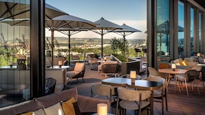 Une terrasse sur le toit, avec des espaces de détente en plein air, de grands parasols et une vue sur le paysage urbain.
