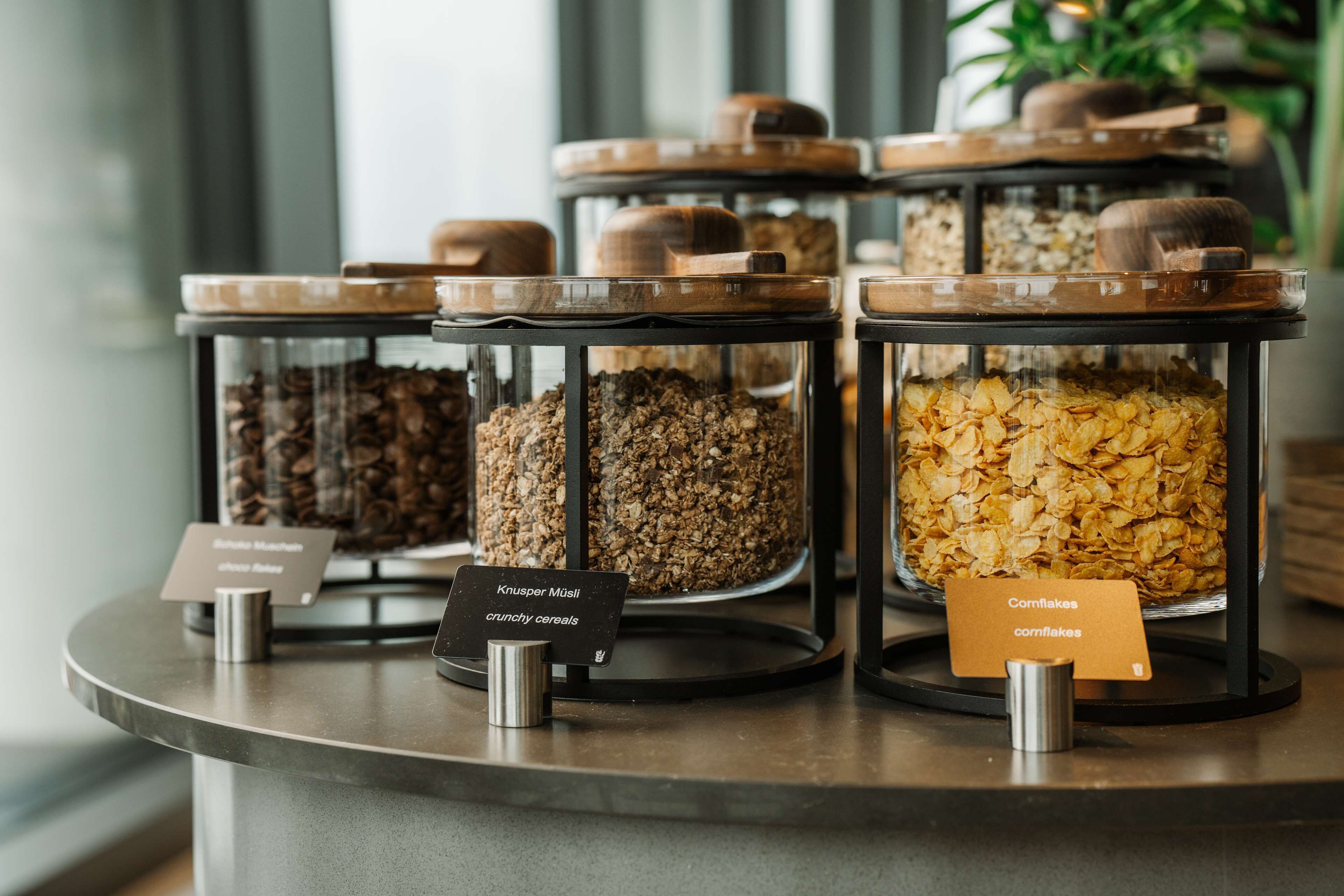 A display of various cereal types in transparent containers with labels.
