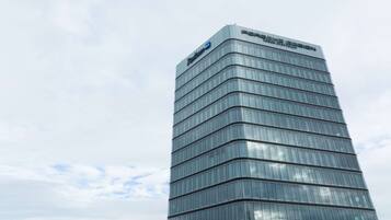 A tall, modern building with a glass facade and the Porsche Design logo at the top.