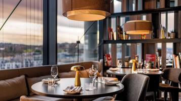 A restaurant with round tables, leather seating, and pendant lighting.