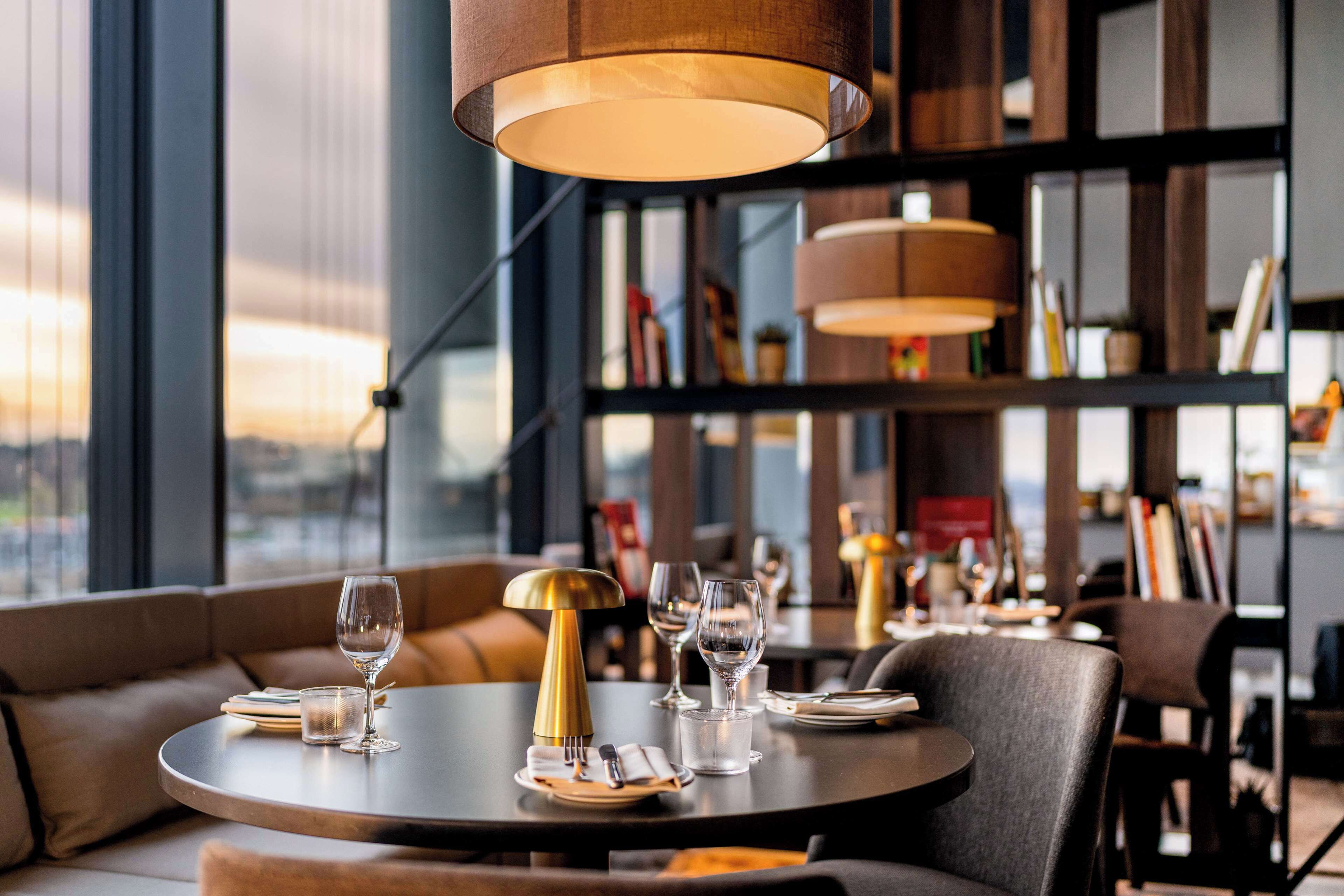A dining area with round tables, a sofa, and a bookshelf in the background.