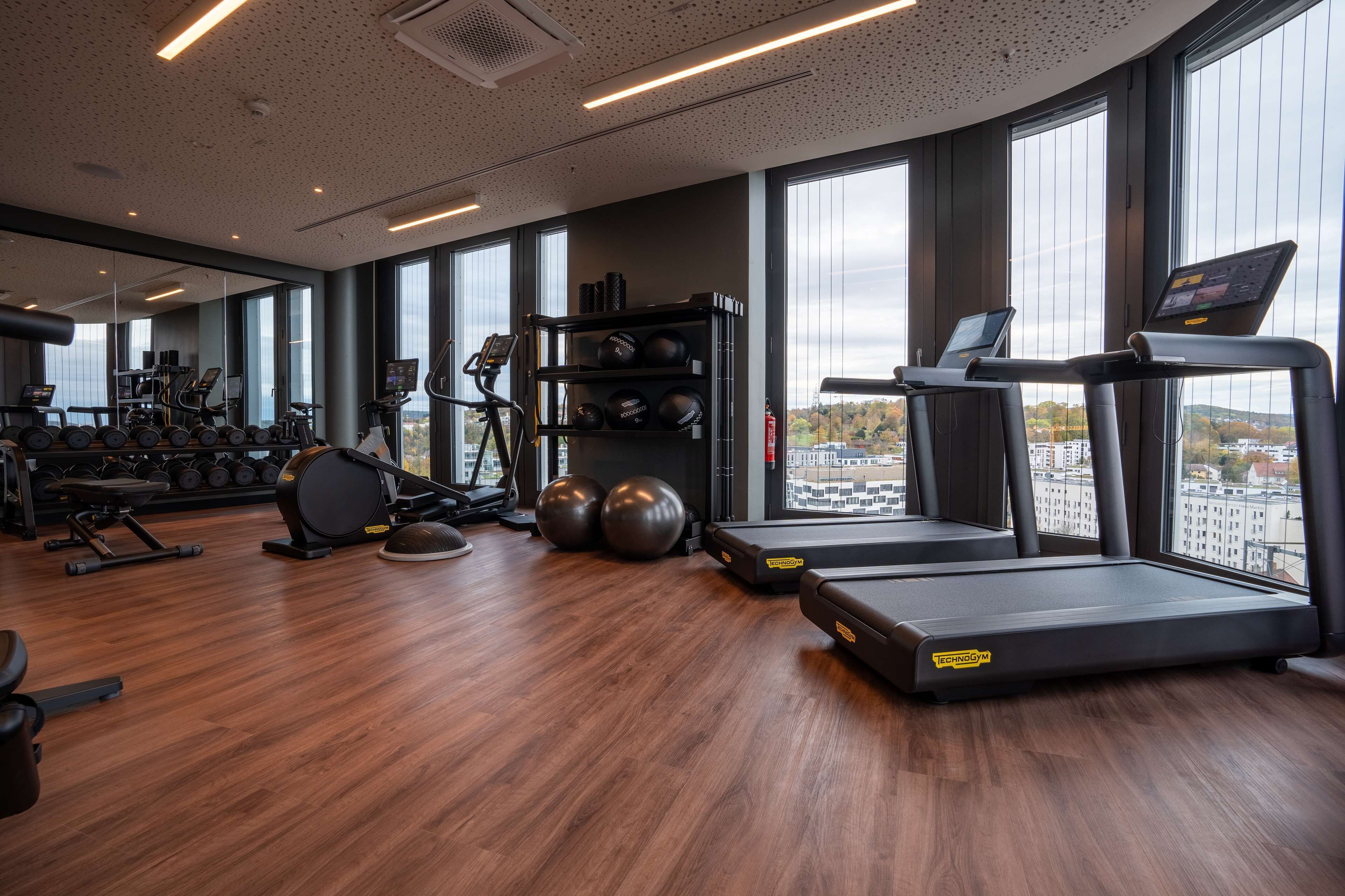 Une salle de sport moderne équipée de tapis de course, de poids et de ballons d’exercice.