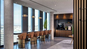 Un bar moderne doté de hauts plafonds, de grandes fenêtres et offrant une vue sur la ville.