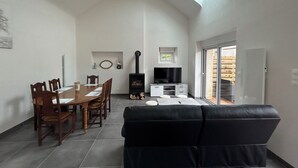 Ett kompakt vardagsrum med en matplats, en svart soffa, en tv och en öppen spis.