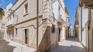 Une rue étroite bordée d’immeubles à l’architecture traditionnelle, avec des balcons et des grilles en fer forgé.