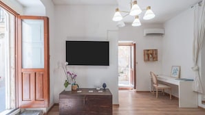 Un salon moderne avec un banc en bois, un téléviseur fixé au mur et un bureau avec une chaise.