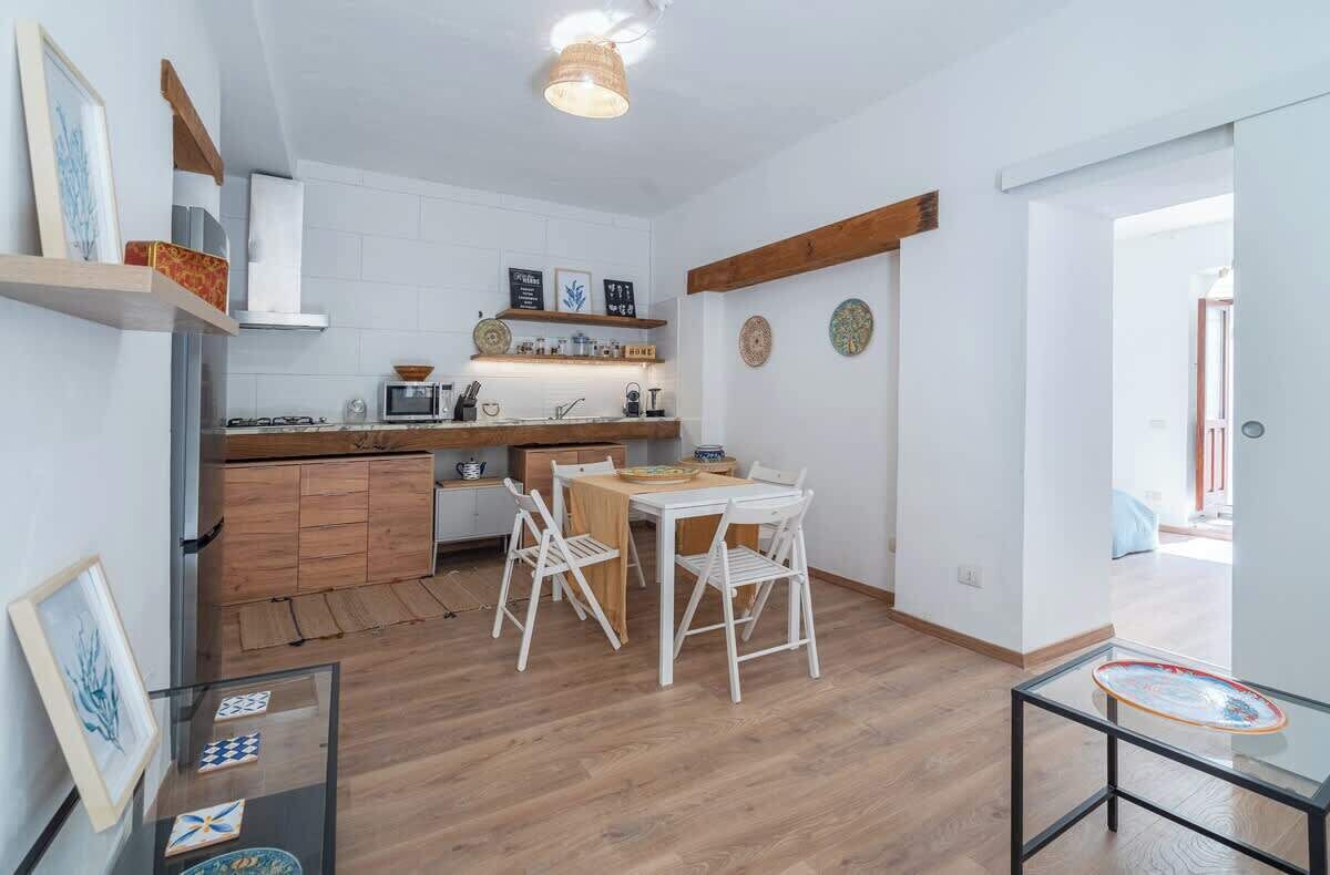 A compact kitchen with white cabinets, a wooden countertop, and a dining area with a white table and chairs.