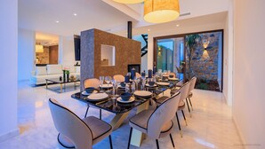 A modern dining area with a long table set for six, surrounded by six chairs. - Villa Martin Stone Las Colinas Golf Country Club (VC)