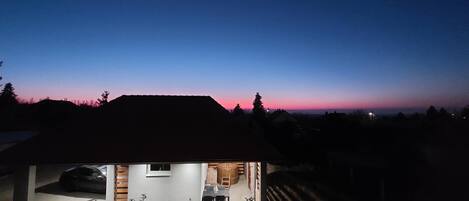 A modern house with a large garage, a visible kitchen area, and a small outdoor seating space.
