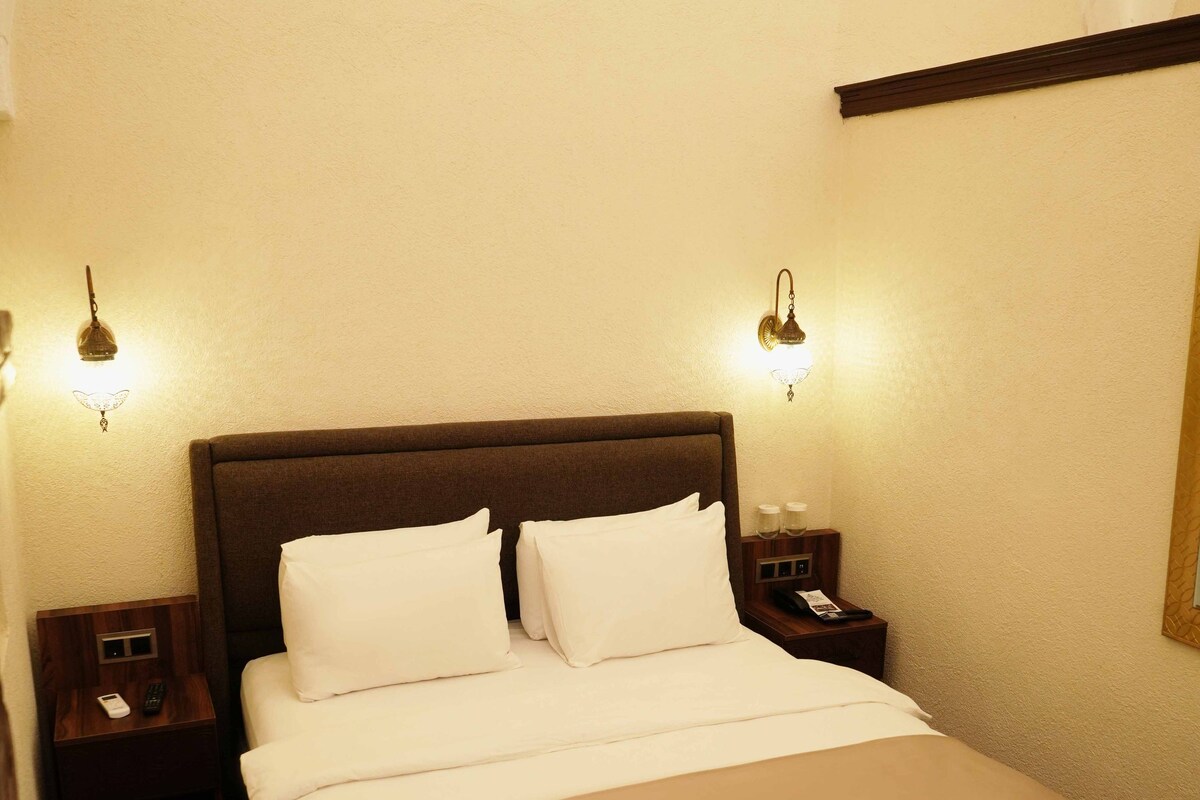 Ein Hotelzimmer mit einem großen Bett, zwei Nachttischen und Wandlampen.