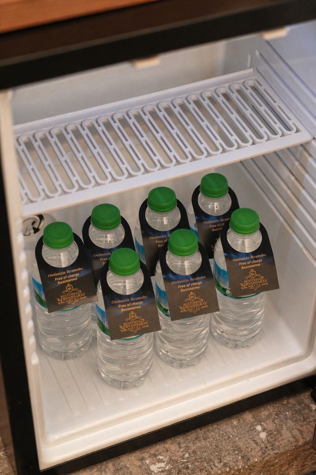 A refrigerator with six water bottles labeled 'Otelimizin ikramdir. Free of charge Beşanlı.'
