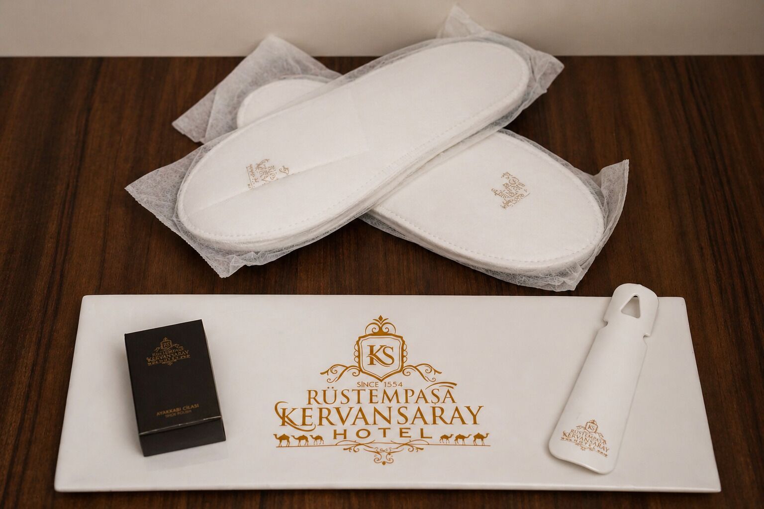 A pair of white slippers, a black box, and a white envelope with hotel branding.