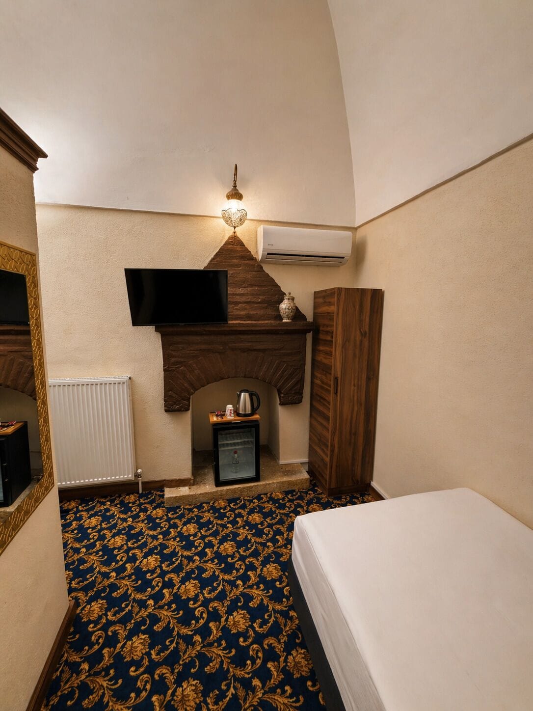 Una habitación de hotel con chimenea, televisor, armario y cama.