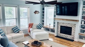 Un salon avec une cheminée, un canapé, une table basse et un téléviseur fixé au mur.